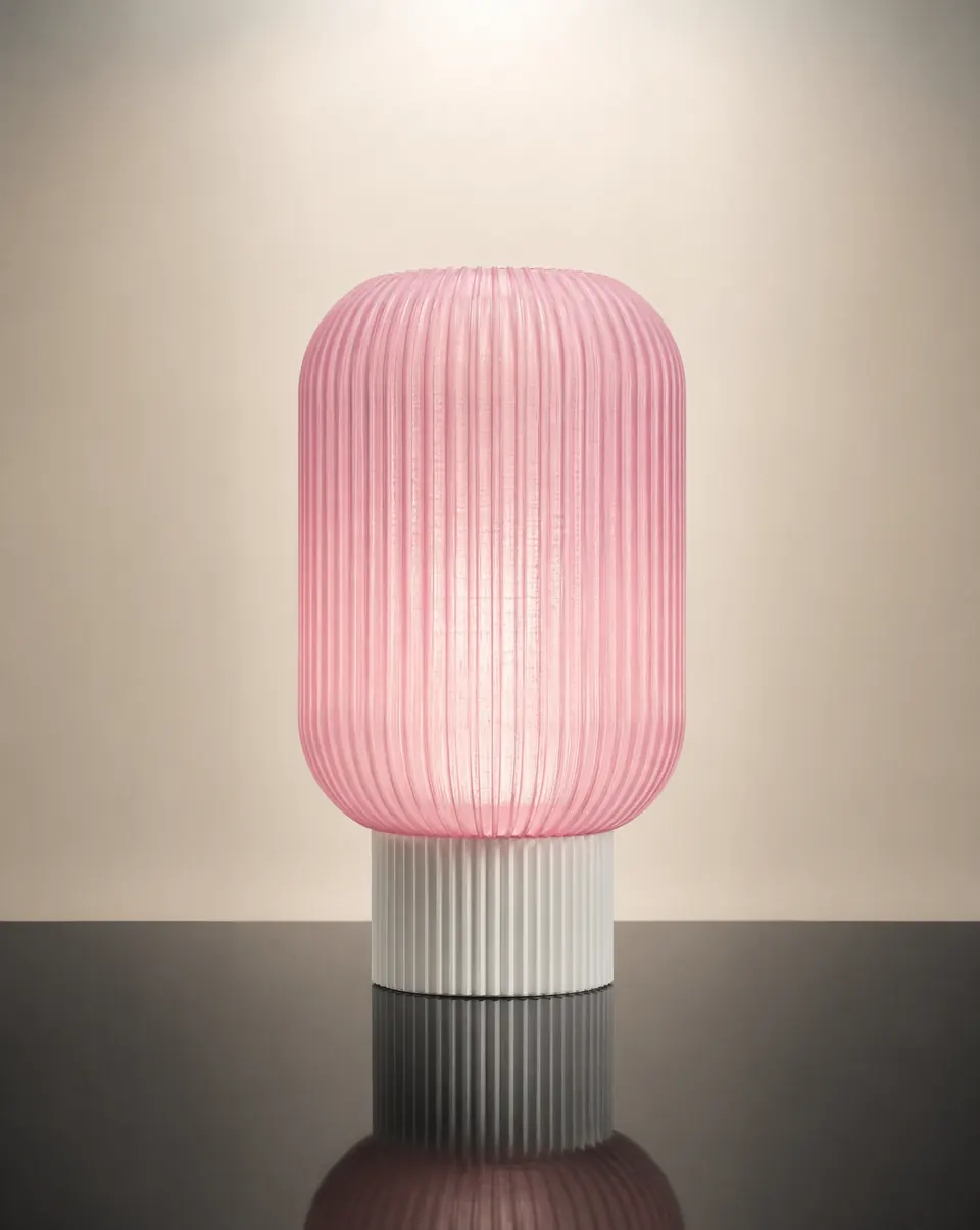 The Noorian table lamp with a blush ribbed printed shade on a dark reflective table