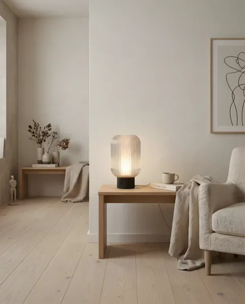 The Altus lamp glowing warmly on a pale oak bench in a calm Scandinavian living room